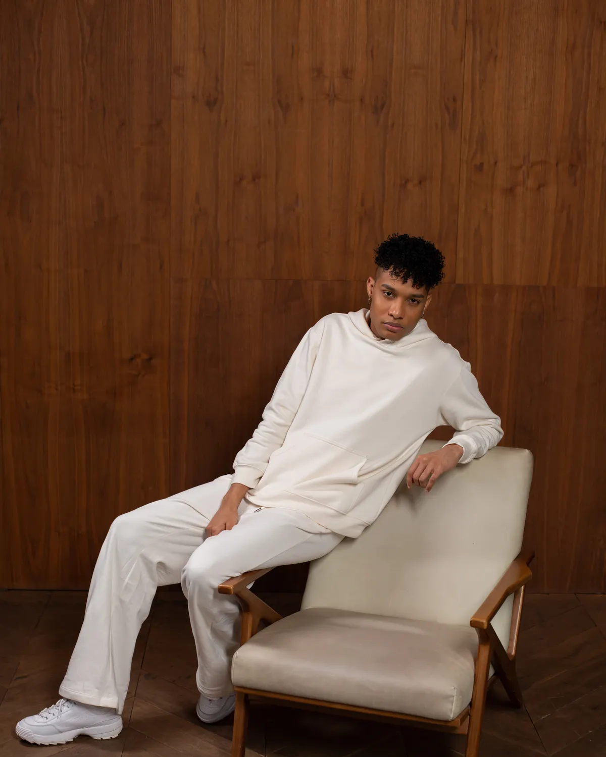 Homem sentado em poltrona vestindo conjunto de moletom off-white oversized